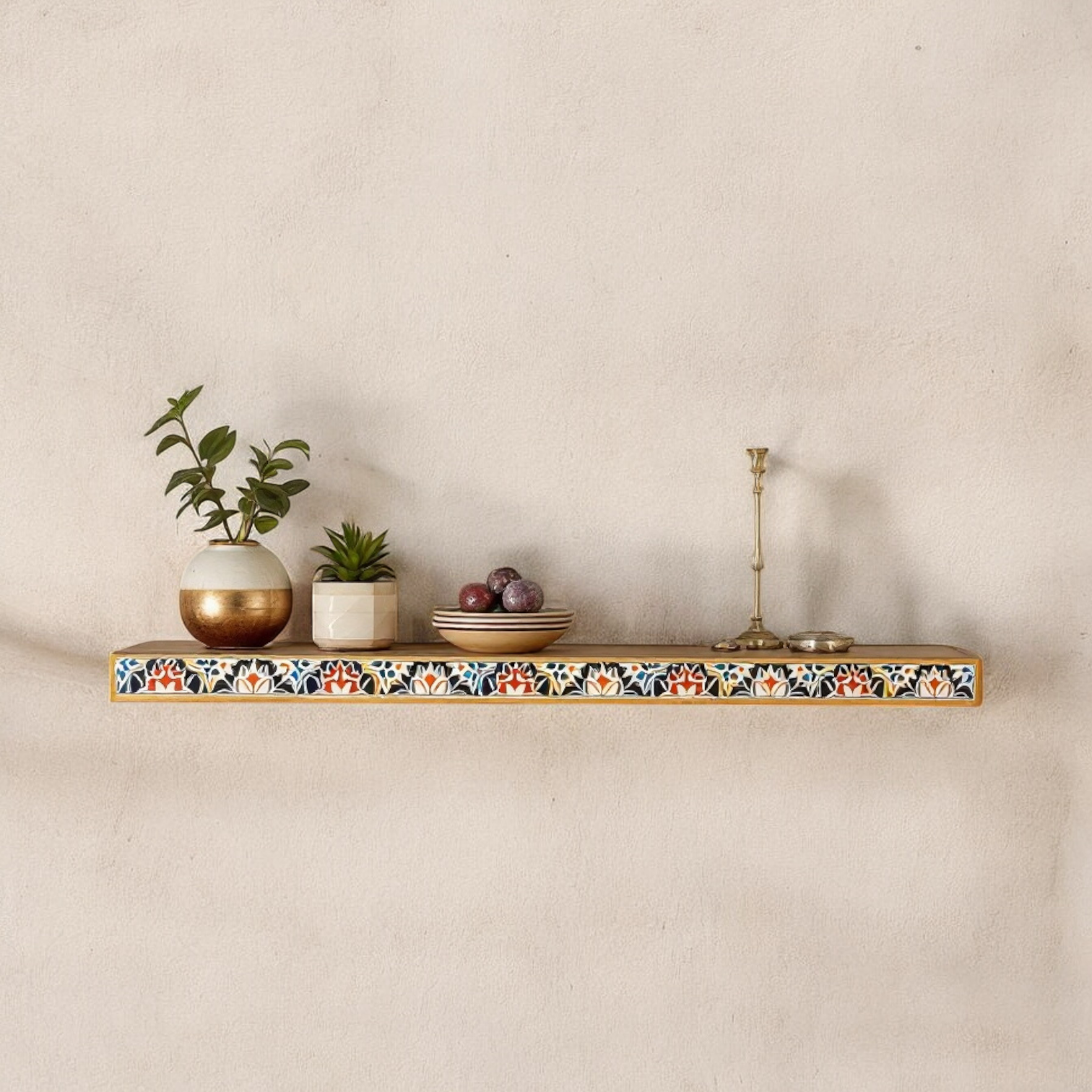 "Long hand-painted wooden wall shelf with a multicolored border, mounted on a textured wall displaying decorative items."