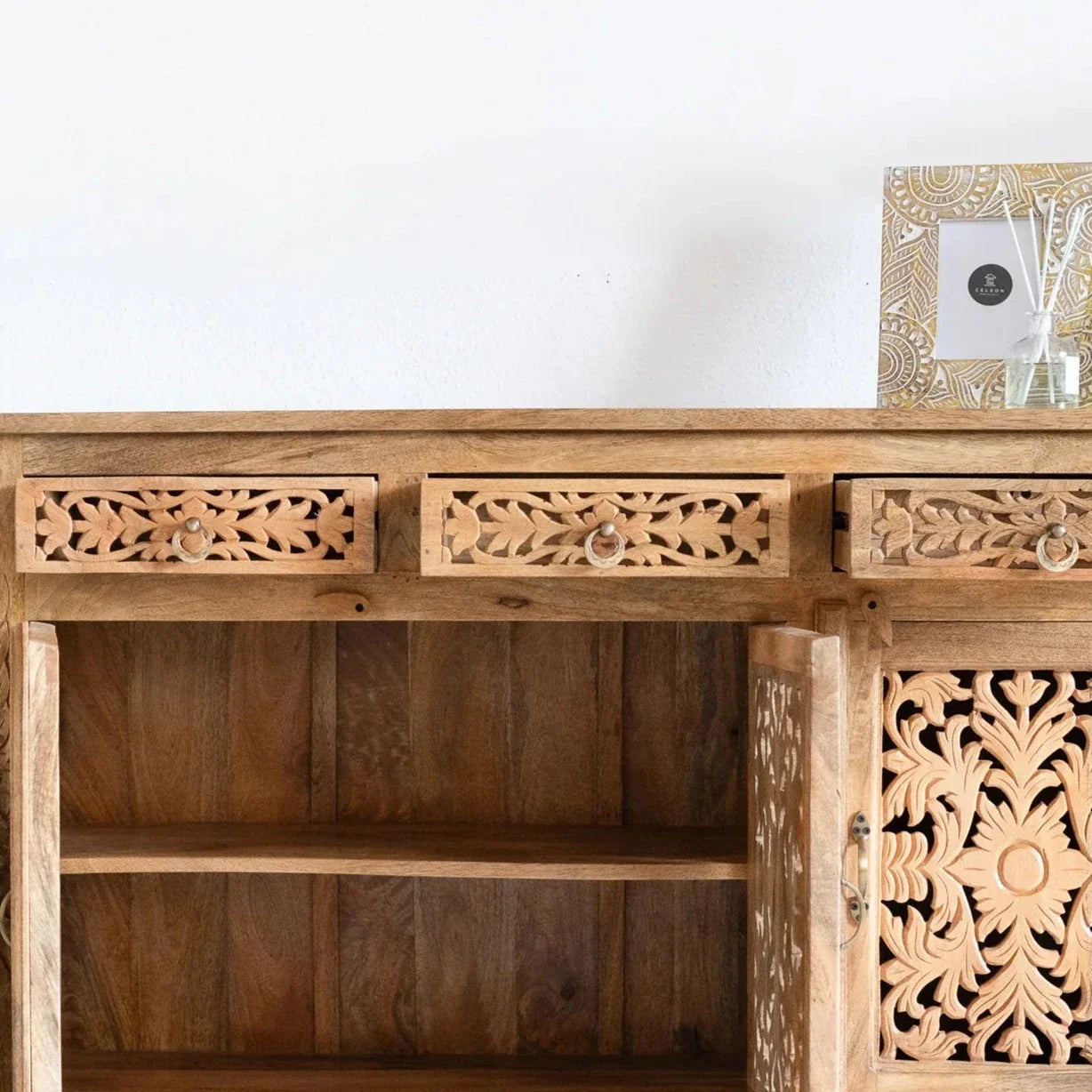 hand carved sideboard, mango wood sideboard, natural finish sideboard, floral carved sideboard, openwork sideboard, 3 door sideboard, 3 drawer sideboard, buffet sideboard, indian carved furniture, storage sideboard, dining room buffet, living room sideboard, entryway sideboard, statement sideboard, medium sideboard, handmade sideboard, artisan made sideboard, premium wood buffet, quality wood furniture, durable sideboard, sturdy buffet, timeless sideboard, elegant buffet, heirloom buffet, rustic sideboard,