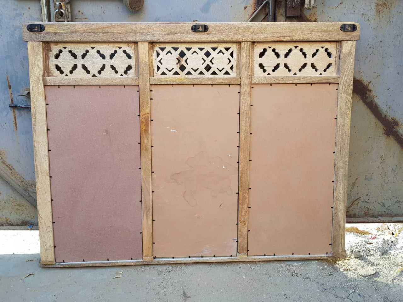 Wooden panel with decorative cutouts on a rusty metal background