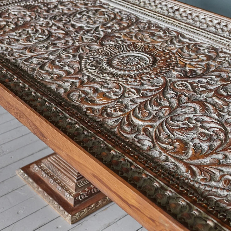 Close-up of a wooden panel with intricate carvings on a light gray floor.