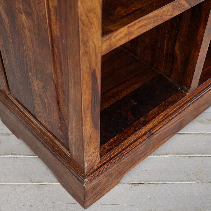 Close-up of a wooden bookshelf corner on a light wooden floor.