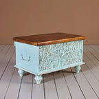 Vintage‑style blue storage trunk on turned legs, lift‑top design.

