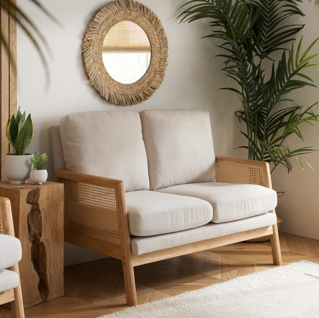 Living room with a wooden sofa, armchair, and coffee table with plants and decor.