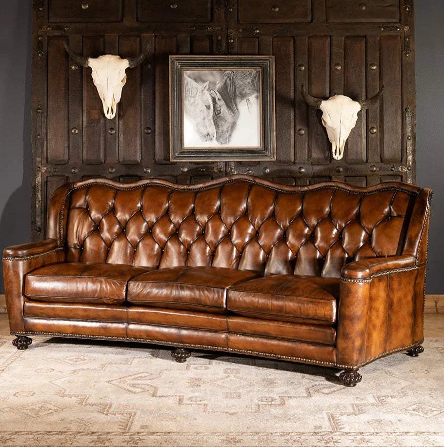 Brown leather sofa in a room with rustic decor including bull skulls and a framed picture.