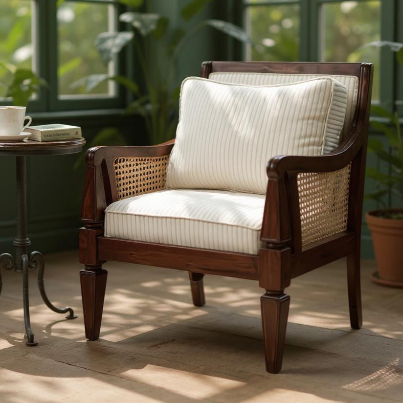 Wooden armchair with white cushion in a room with large windows and plants