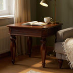 Cozy living room with a wooden side table, lamp, and sofa with a blanket.