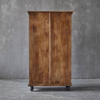 Wooden wardrobe with a rustic finish against a gray wall.