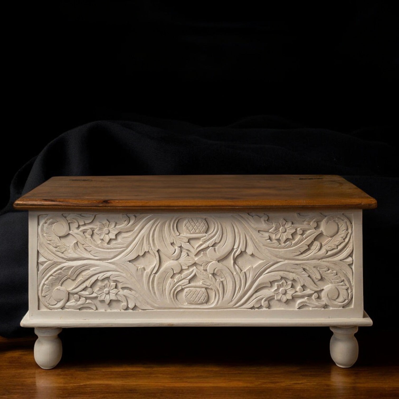Mango wood treasure chest with white distressed finish and natural wood lid, featuring intricate floral carvings.

